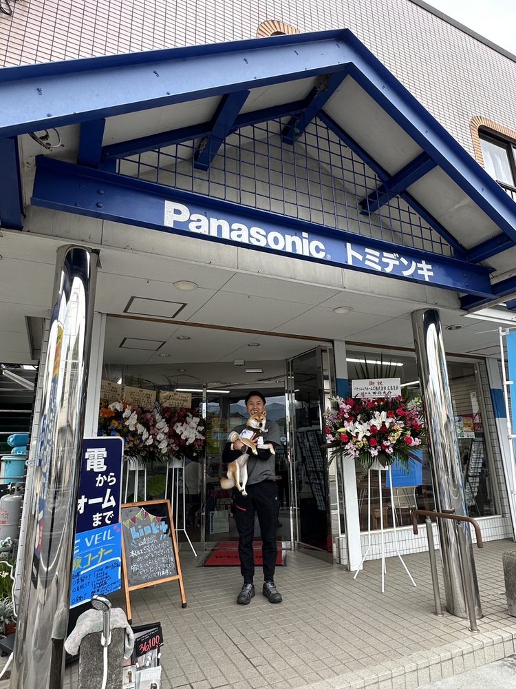 Ｌｉｎｋプラス トミデンキ由宇店の店頭に立つ代表 浴中優輝と看板犬のうにちゃん
