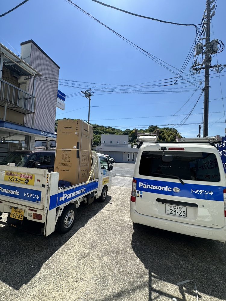 店頭に並ぶトミデンキの配達用トラックとサービスカー